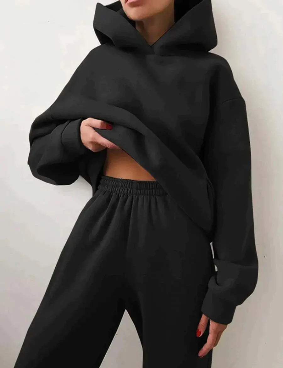 Donna con felpa nera oversize e pantaloni coordinati, moda casual, abbigliamento comodo, stile streetwear, tendenza autunno inverno.