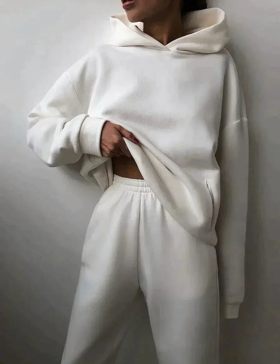 Donna con felpa bianca oversize e pantaloni coordinati, moda casual minimalista, abbigliamento comodo, stile streetwear moderno.