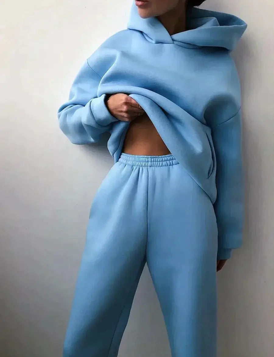 Donna in tuta sportiva azzurra, felpa con cappuccio e pantaloni comodi. Abbigliamento casual, moda donna, stile rilassato.