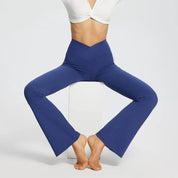 Pantaloni a zampa blu da donna, vita alta, indossati con top bianco. Abbigliamento sportivo elegante, comodo per yoga e fitness.