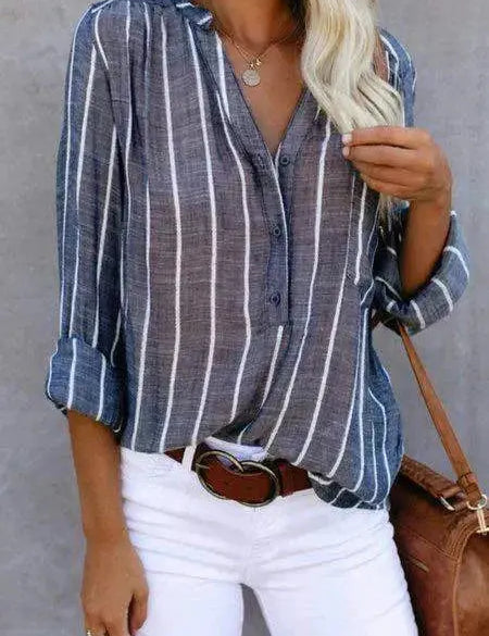 Camicia a righe verticali blu e bianche da donna, maniche lunghe, abbinata a pantaloni bianchi e cintura marrone. Stile casual elegante.