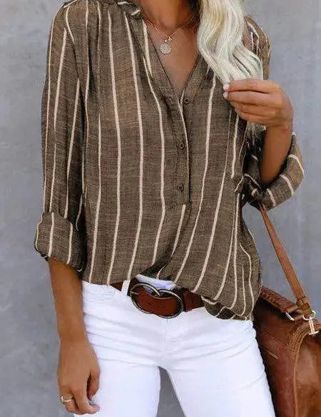 Camicia a righe verticali marrone e bianca, maniche lunghe, abbinata a pantaloni bianchi. Stile casual elegante, moda donna autunnale.