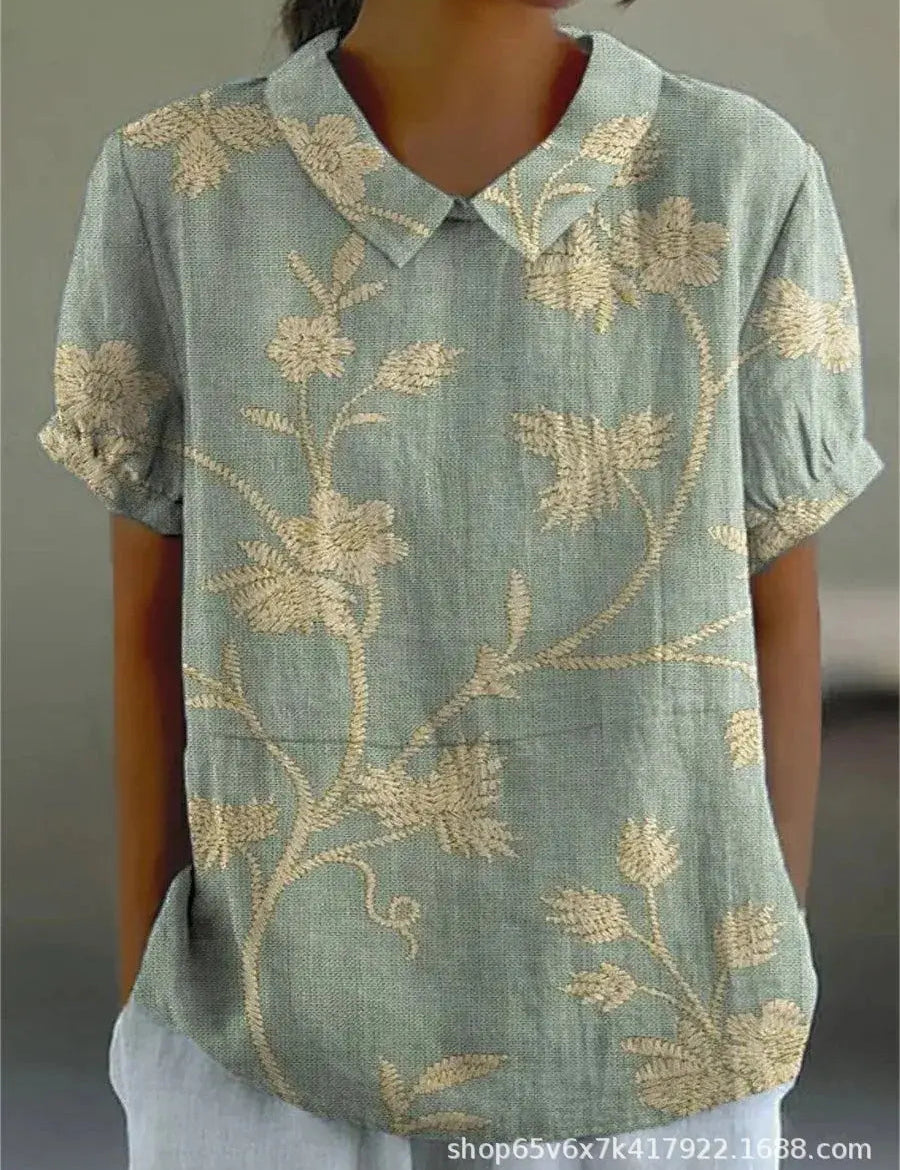 Camicia donna verde con ricami floreali beige, maniche corte, colletto classico. Elegante e casual, perfetta per moda estiva.