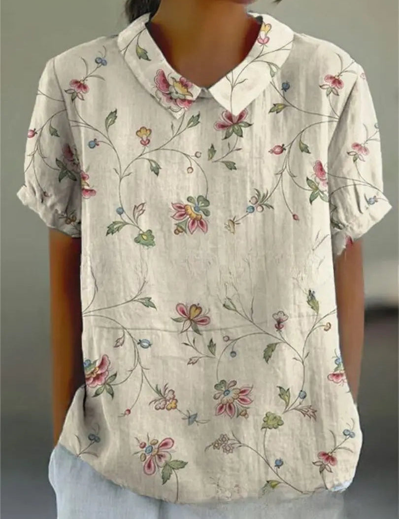 Camicia donna in cotone bianco con colletto, maniche corte e stampa floreale colorata. Moda estiva casual, abbigliamento femminile elegante.
