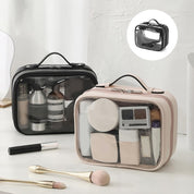 Due beauty case trasparenti con cerniera, uno nero e uno beige, contenenti cosmetici e accessori per il trucco, su sfondo bianco.