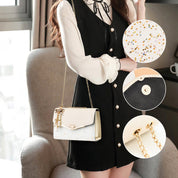Donna con borsa a tracolla bianca decorata con stelle dorate, dettagli in pelle nera e catena dorata. Elegante abbigliamento da giorno.