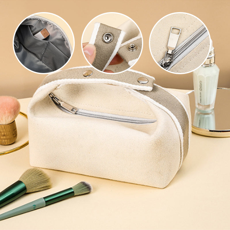 Borsa cosmetica in tela beige con cerniera, dettagli interni, chiusura a bottone e manico. Accessori trucco e crema viso sullo sfondo.