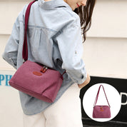 Donna con borsa a tracolla in tela rosa, design casual, indossa camicia di jeans. Borsa leggera, ideale per uso quotidiano e moda urbana.