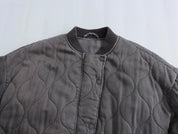 Giacca trapuntata grigia con bottoni a pressione, colletto a coste, design ondulato. Moda autunnale, abbigliamento casual, stile moderno.