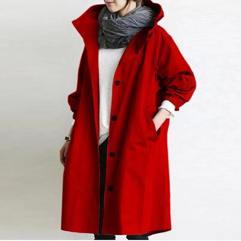 Cappotto rosso donna con cappuccio, bottoni neri, tasche laterali, abbinato a sciarpa grigia e maglia bianca. Moda autunno inverno elegante.