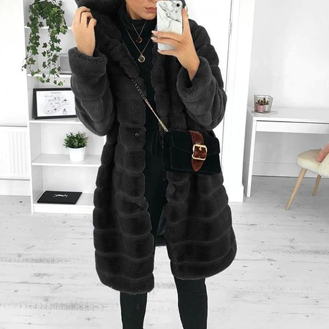 Donna con cappotto di pelliccia sintetica nero, borsa a tracolla elegante, in un ambiente moderno. Moda invernale, abbigliamento donna chic.