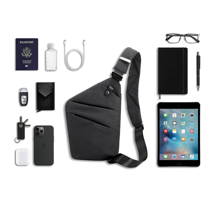 Borsa a tracolla nera con accessori: passaporto, iPad, occhiali, penna, quaderno, smartphone, chiavi, auricolari, cavo USB, portafoglio, disinfettante.