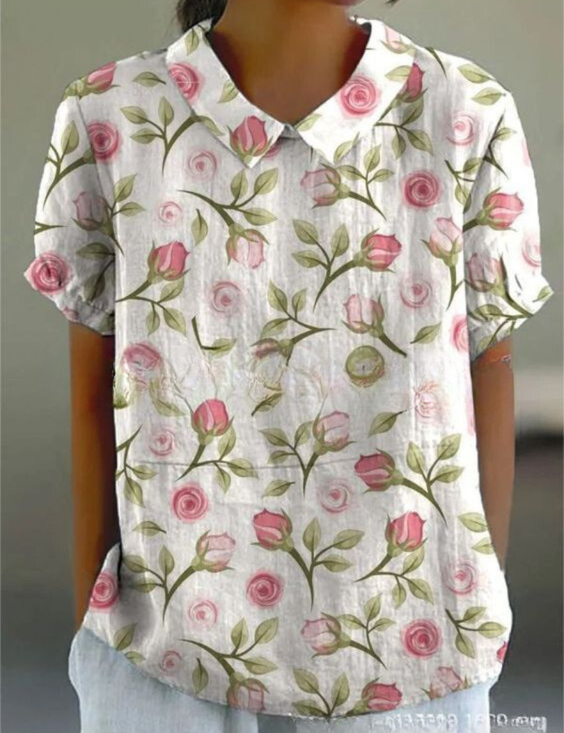 Camicia donna a maniche corte con stampa floreale rosa su sfondo bianco, colletto classico. Moda estiva casual, tessuto leggero e traspirante.