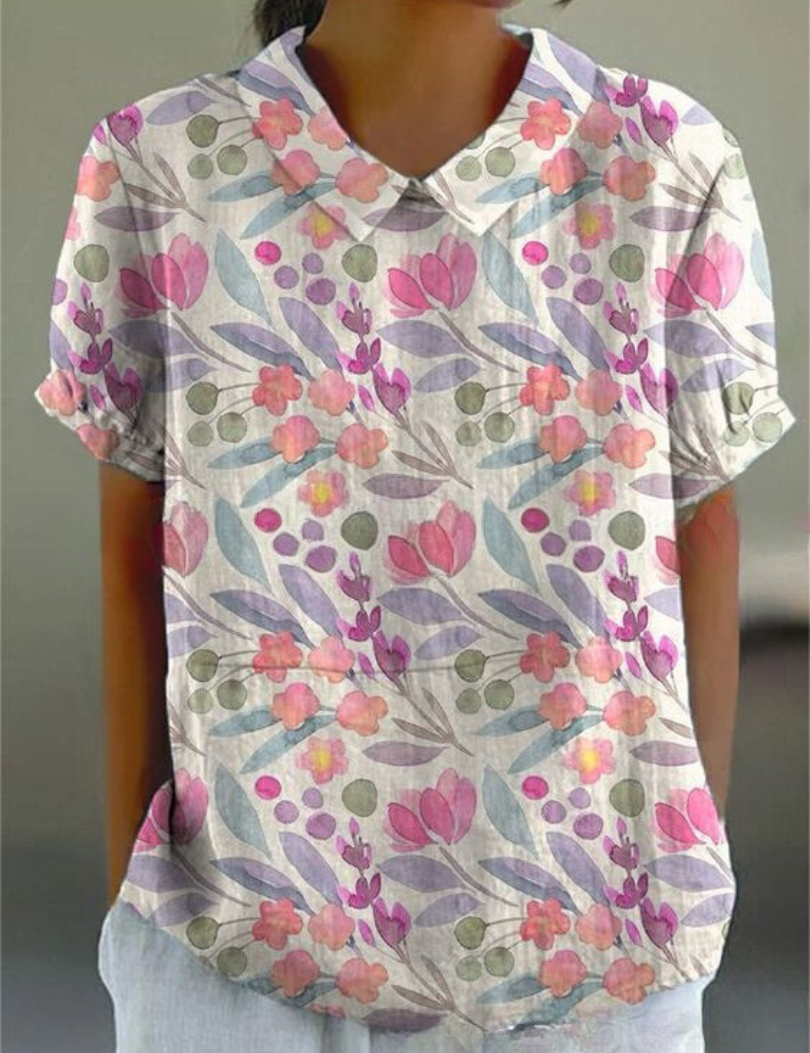 Camicia donna a maniche corte con stampa floreale colorata, colletto classico, sfondo bianco. Stile casual estivo, moda femminile.