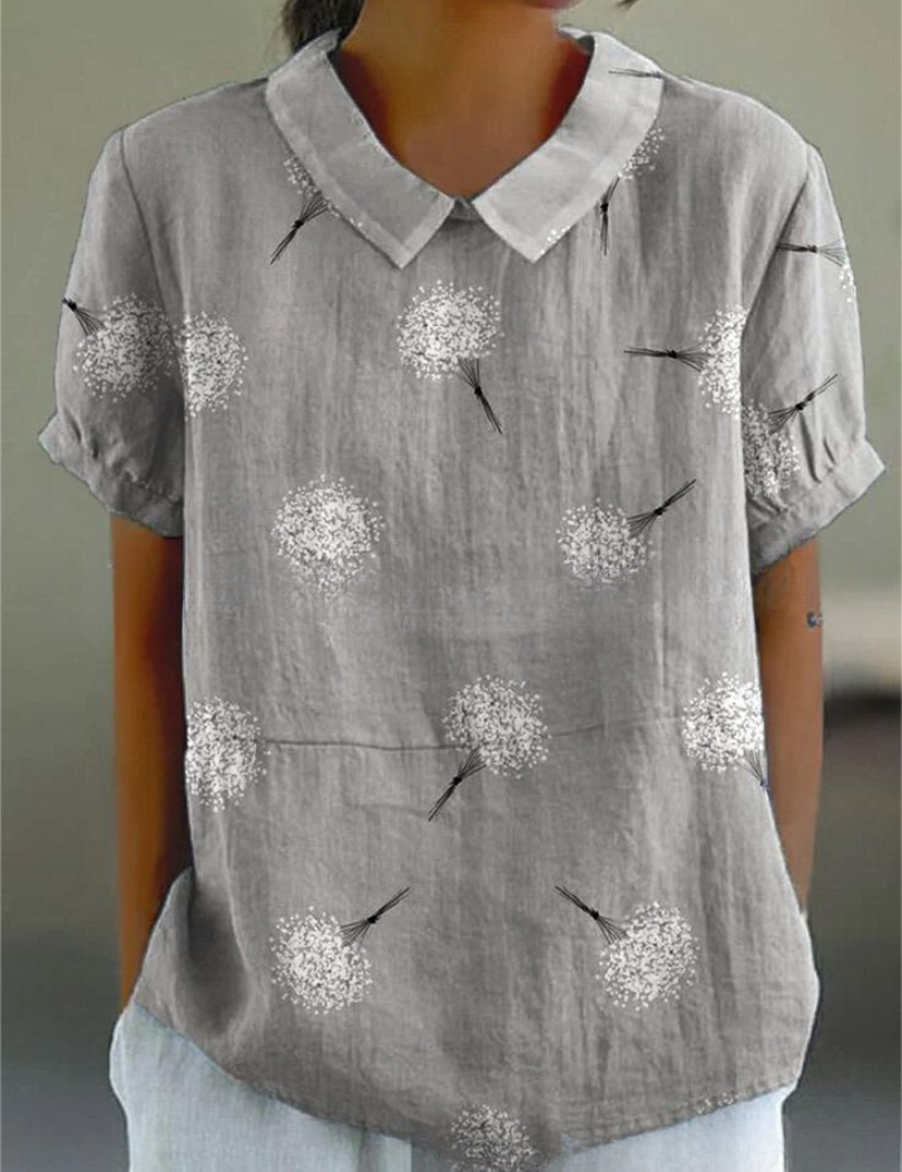 Blusa grigia da donna con colletto, maniche corte e stampa di soffioni bianchi. Stile casual, tessuto leggero, ideale per l'estate.