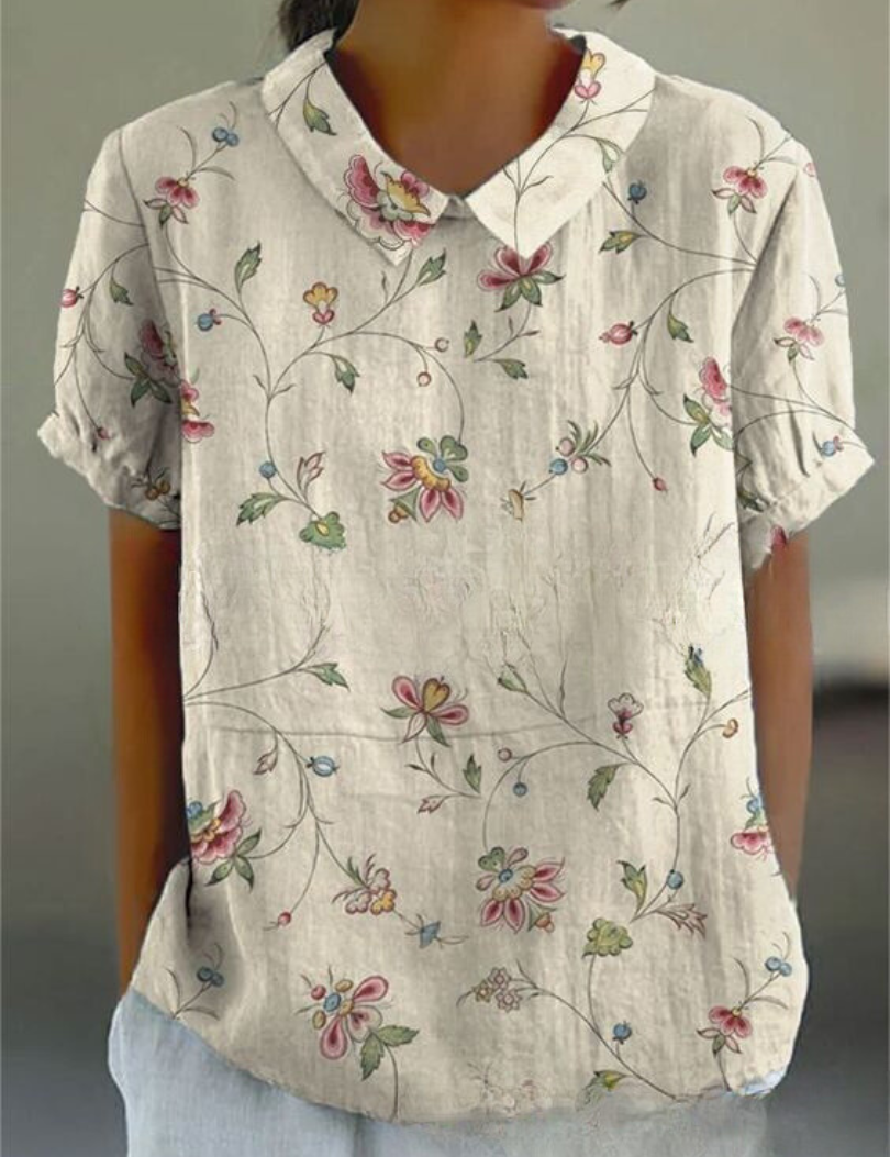 Camicia donna in lino bianco con colletto, maniche corte e stampa floreale colorata. Elegante e casual, ideale per la moda estiva.