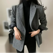 Giacca donna elegante grigia, stile casual chic, abbinata a maglione nero. Moda autunnale, outfit versatile per ufficio o uscite informali.