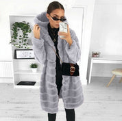 Donna con cappotto in pelliccia sintetica grigia, occhiali da sole e borsa a tracolla nera. Moda invernale elegante e moderna.