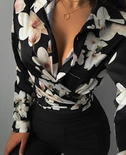 Camicia donna a fiori bianchi su sfondo nero, scollatura profonda, abbinata a pantaloni neri. Elegante e alla moda, perfetta per serate.