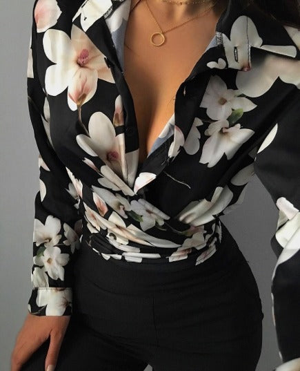 Camicia donna a fiori bianchi su sfondo nero, scollatura profonda, abbinata a pantaloni neri. Elegante e alla moda, perfetta per serate.