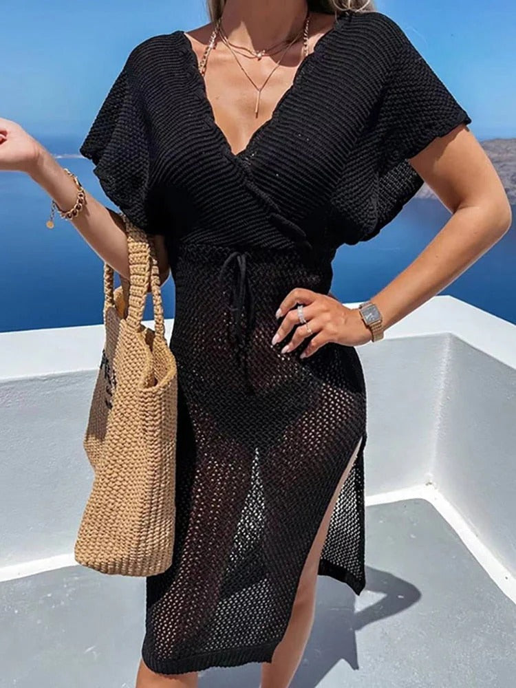 Donna con abito nero trasparente estivo, borsa di paglia, sfondo marino. Moda estiva, abbigliamento da spiaggia, stile elegante.