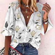Camicia donna floreale bianca con bottoni, maniche corte, abbinata a jeans. Accessori: collane, orologio, borsa leopardata. Moda estiva casual.