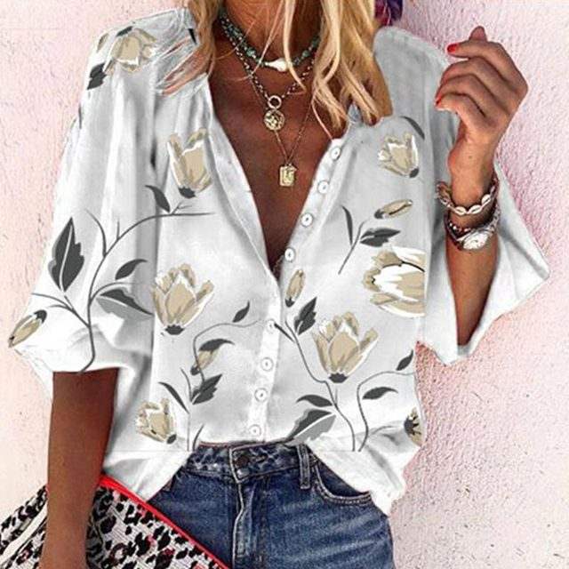 Camicia donna floreale bianca con bottoni, maniche corte, abbinata a jeans. Accessori: collane, orologio, borsa leopardata. Moda estiva casual.