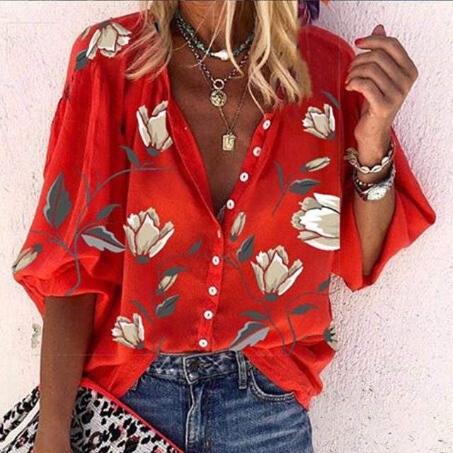Camicia rossa floreale da donna con bottoni, maniche ampie, abbinata a jeans. Accessori: collane e bracciale. Moda estiva casual.
