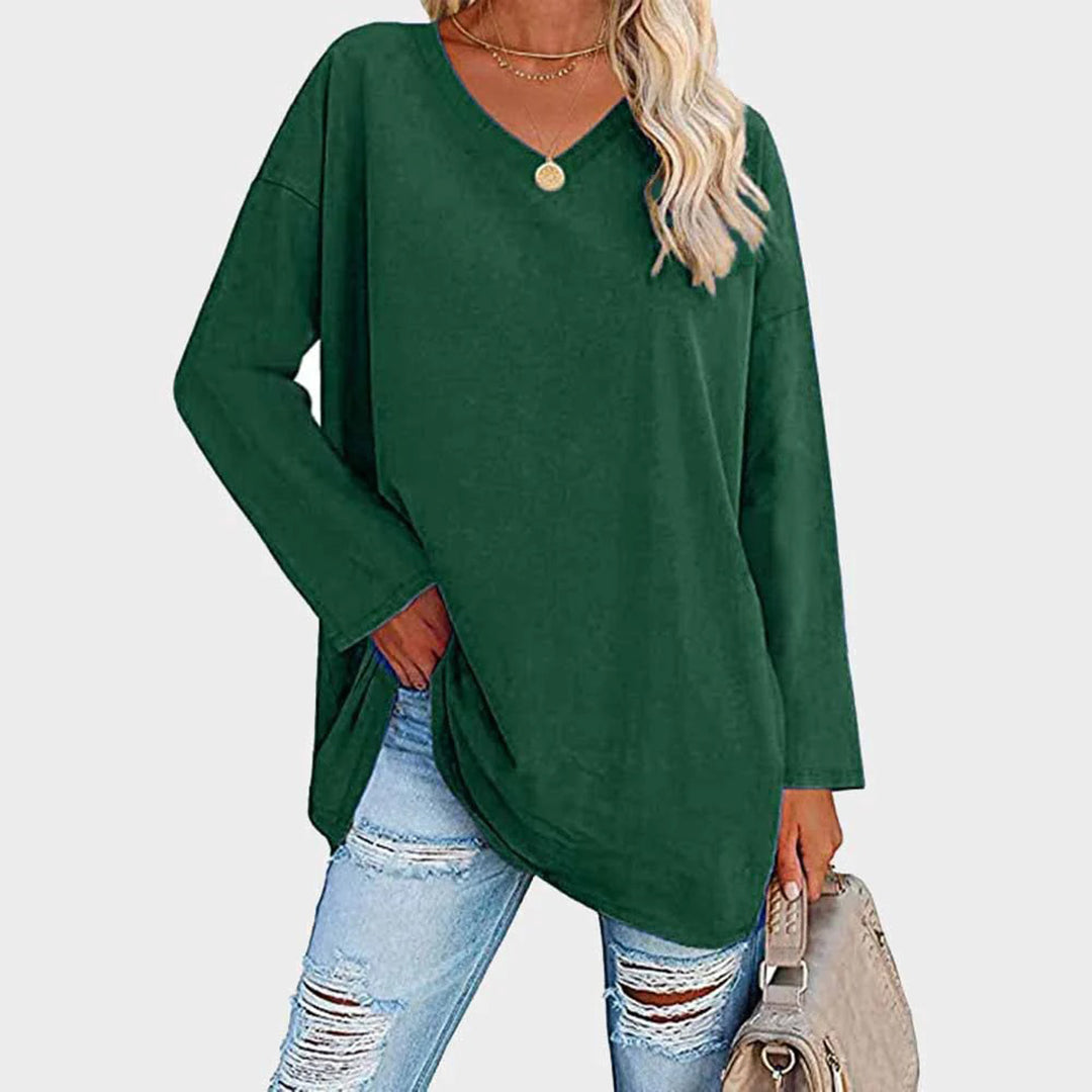 Maglia verde donna a maniche lunghe, scollo a V, abbinata a jeans strappati e borsa beige. Moda casual autunnale.