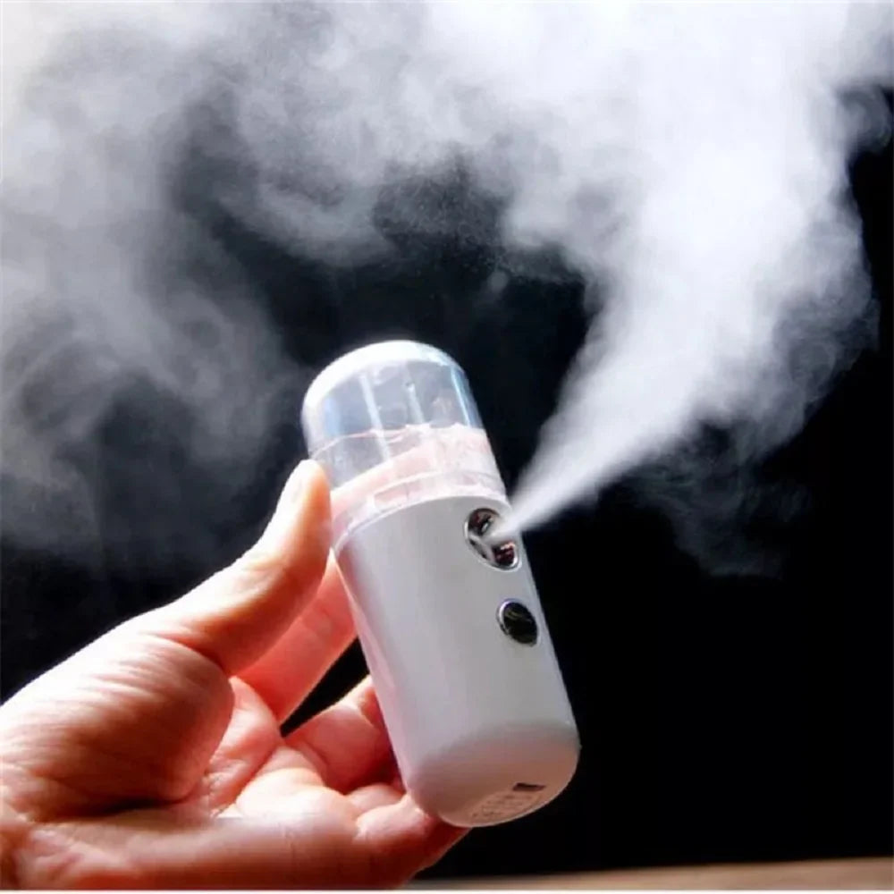 Umidificatore portatile bianco a vapore, tenuto in mano, con design compatto e serbatoio trasparente. Ideale per idratazione viso e pelle.