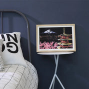 Quadro decorativo con paesaggio giapponese, pagoda e Monte Fuji, su tavolino bianco in camera da letto moderna. Arredamento casa elegante.