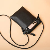 Borsa a tracolla in pelle nera con smartphone in tasca, design elegante e compatto, accessorio moda donna, ideale per uso quotidiano.