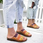 Sandali multicolore in pelle con suola in sughero, indossati da una persona con jeans strappati. Scarpe estive casual, moda donna.
