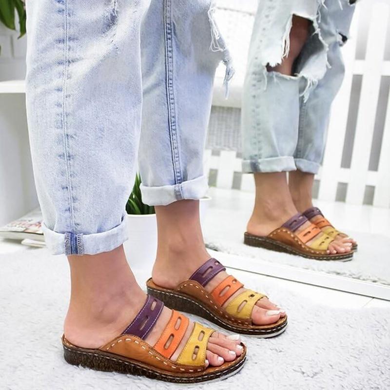 Sandali multicolore in pelle con suola in sughero, indossati da una persona con jeans strappati. Scarpe estive casual, moda donna.
