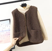 Gilet in pile marrone su maglione beige, appeso su gruccia. Moda autunno inverno, abbigliamento caldo e confortevole, stile casual elegante.