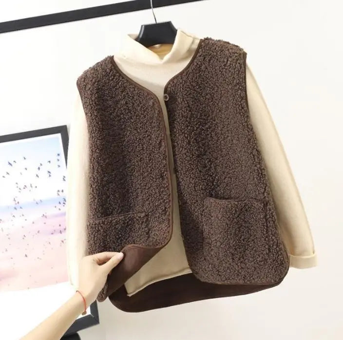 Gilet in pile marrone su maglione beige, appeso su gruccia. Moda autunno inverno, abbigliamento caldo e confortevole, stile casual elegante.