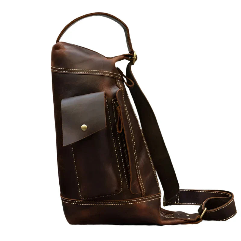 Zaino monospalla in pelle marrone, design elegante con tasca frontale con bottone, ideale per uomo, perfetto per viaggi e uso quotidiano.