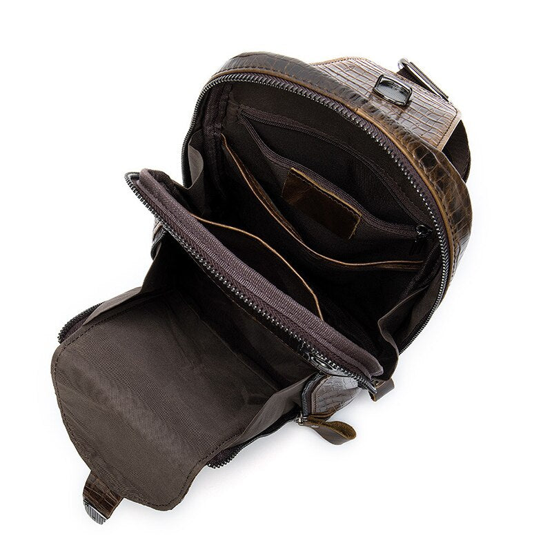 Zaino in pelle marrone con texture coccodrillo, aperto per mostrare scomparti interni spaziosi e tasche multiple. Design elegante e funzionale.