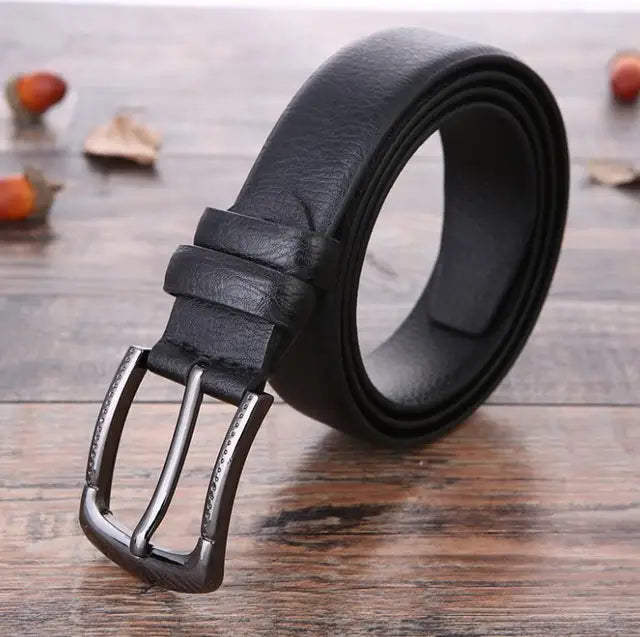 Cintura in pelle nera da uomo su tavolo in legno, fibbia in metallo argentato, accessorio moda elegante, alta qualità, stile classico.