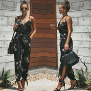 Donna con tuta nera floreale, sandali con tacco e borsa a tracolla. Moda estiva elegante, look casual chic. Sfondo in legno e piante.