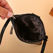 Borsa a tracolla nera in pelle con interno foderato, chiusura a zip, design elegante e compatto. Accessorio moda donna, ideale per ogni occasione.
