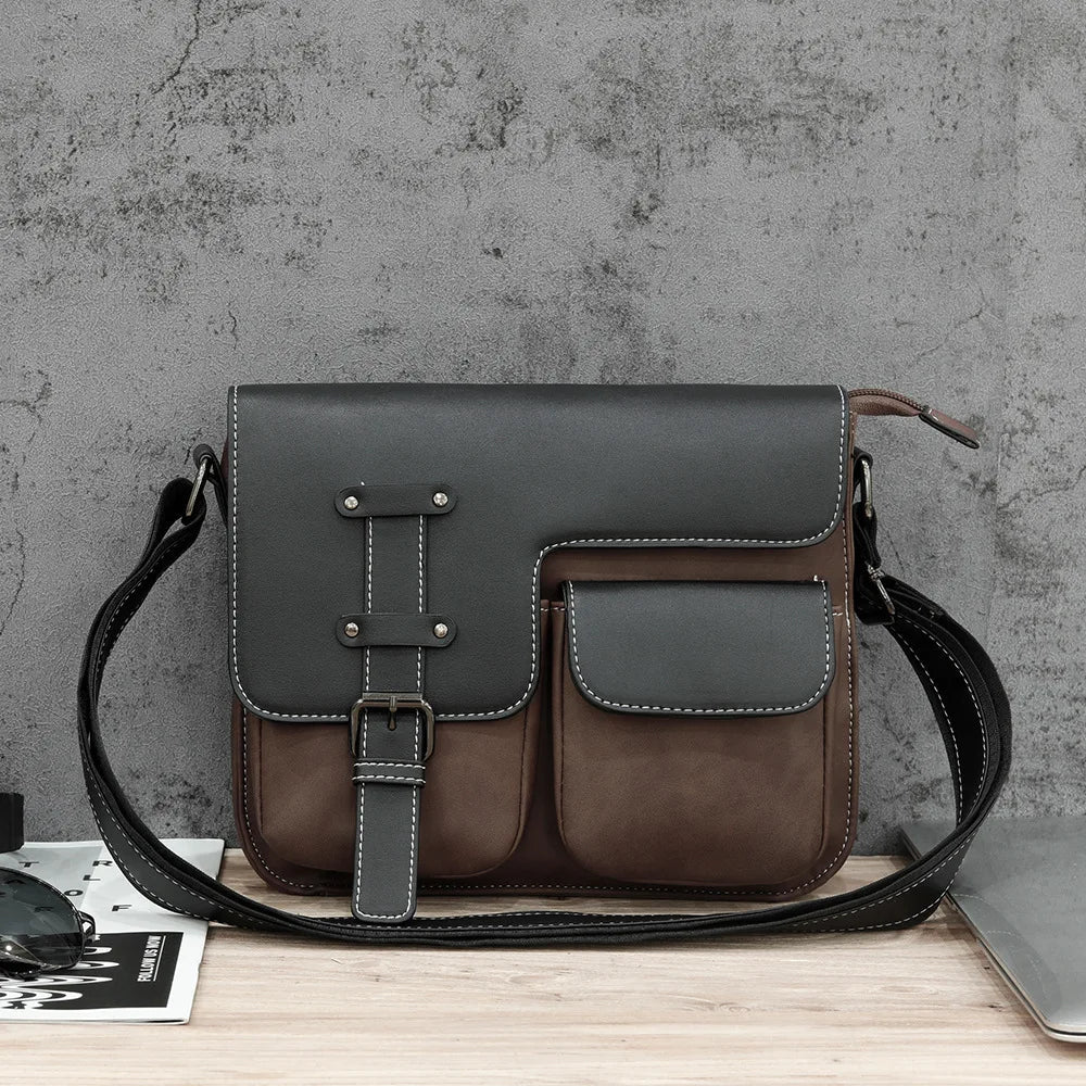 Borsa a tracolla in pelle marrone e nera su sfondo grigio, design elegante con tasche frontali, ideale per uomo, accessorio moda casual.