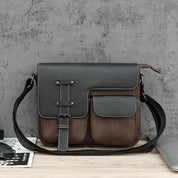 Borsa a tracolla in pelle marrone e nera su sfondo grigio, design elegante con tasche frontali, ideale per uomo, accessorio moda casual.