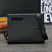 Elegante borsa a tracolla nera in pelle, design minimalista, con manico integrato e tasca frontale, su sfondo moderno. Accessorio moda uomo.