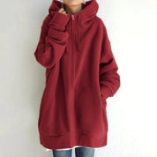 Felpa oversize rossa con cappuccio, zip frontale e tasche laterali, indossata da una persona. Abbigliamento casual autunnale, moda streetwear.