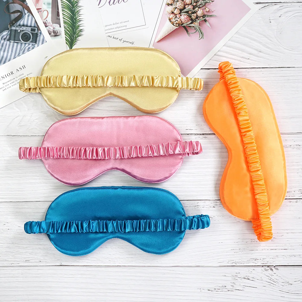 Quattro mascherine per dormire in seta colorata (giallo, rosa, arancione, blu) su sfondo bianco, ideali per relax e sonno profondo.