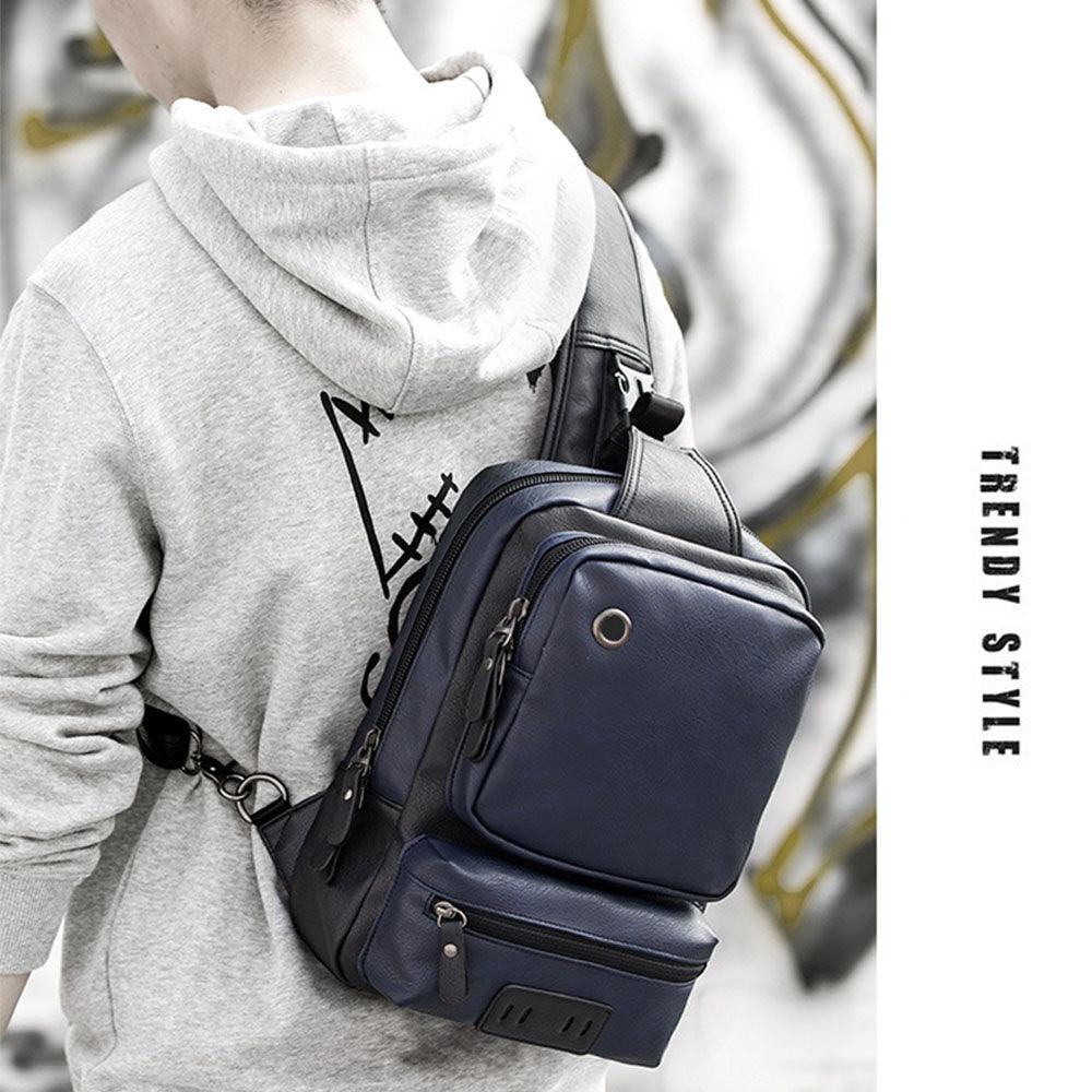 Zaino a tracolla in pelle blu scuro, indossato da una persona con felpa grigia. Design moderno, ideale per moda urbana e viaggi.