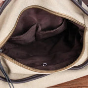 Zaino in tela beige aperto, interno marrone con tasche multiple. Design spazioso, ideale per viaggi e uso quotidiano. Accessorio moda unisex.