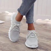 Scarpe da ginnastica bianche da donna, design traspirante in maglia, suola antiscivolo, indossate con jeans. Ideali per sport e tempo libero.