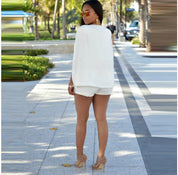 Donna in abbigliamento estivo bianco, occhiali da sole, tacchi alti beige, cammina su un viale alberato. Moda estiva, stile elegante, look casual.